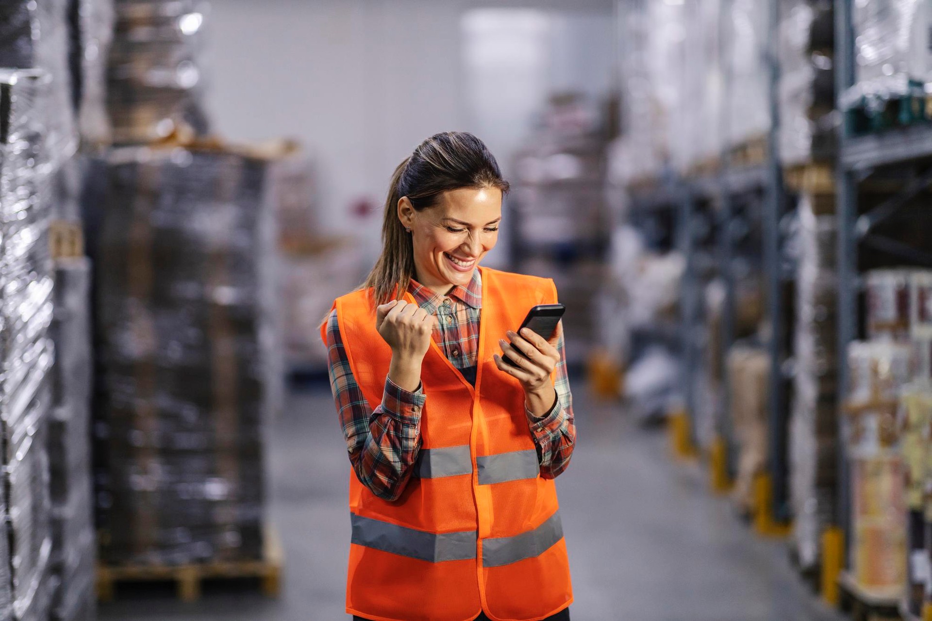 Lagermitarbeiterin nutzt eine App auf dem Smartphone im Lager