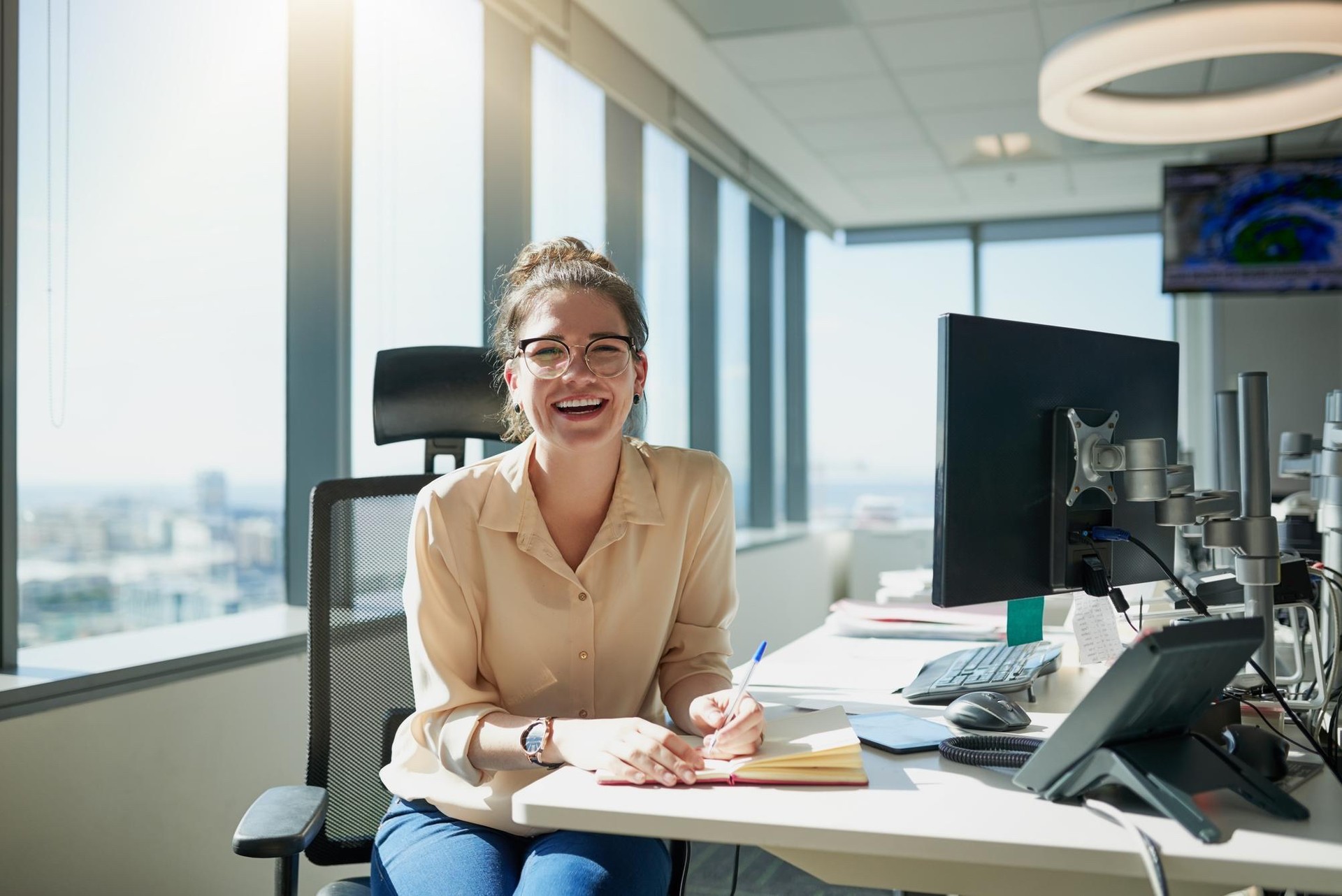 Mitarbeiterin am Schreibtisch im Büro mit Monitor