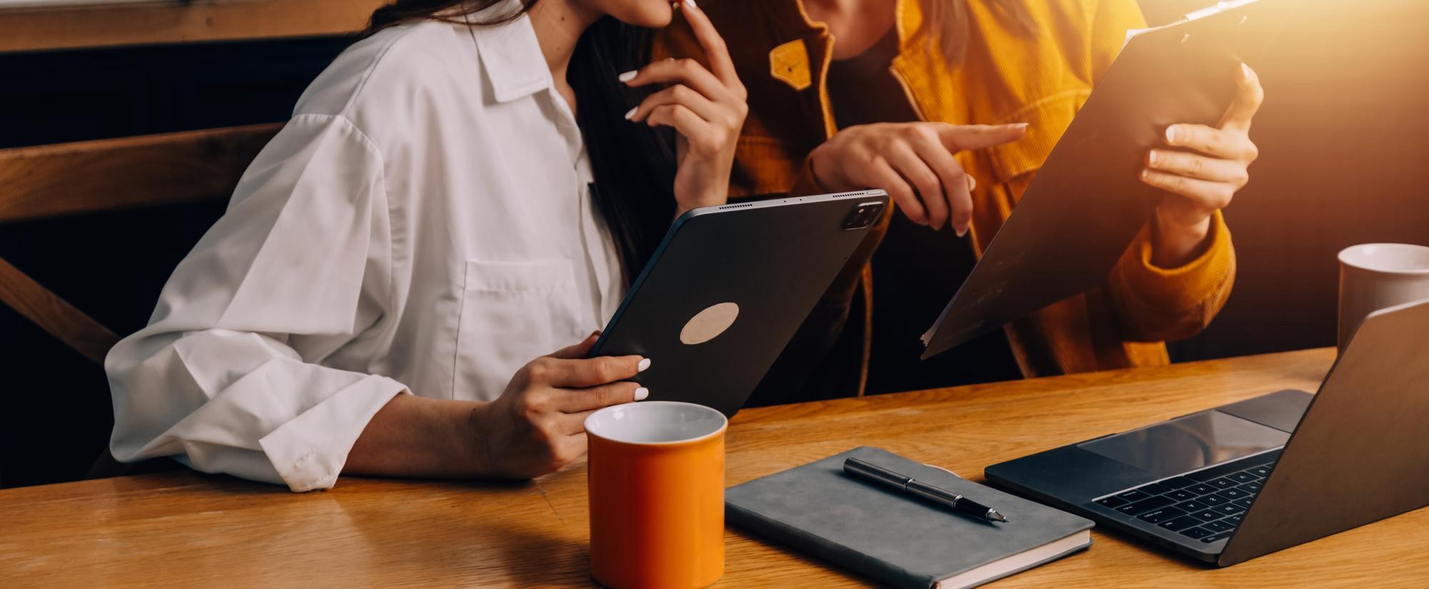 Zwei Personen besprechen ein Web-Projekt mit Tablet und Laptop
